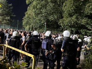 zdjęcie kolorowe: policjanci oddziału prewencji w asyście kroczącej i kibice przy bramie wejściowej na katowicki stadion