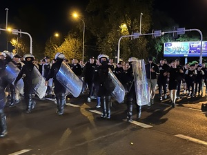 zdjęcie kolorowe: policjanci oddziału prewencji w asyście kroczącej prowadzą kibiców na dworzec pkp