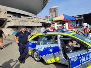 zdjęcie kolorowe: policjant przy radiowozie przed katowickim Spodkiem podczas pikniki integracyjnego