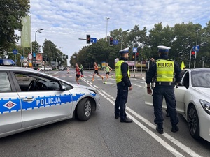 zdjęcie kolorowe: policjanci katowickiej drogówki na skrzyżowaniu zabezpieczają uczestników maratonu