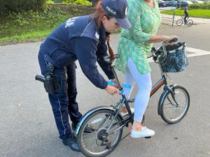 zdjęcie kolorowe: katowicka policjantka wręczający elementy odblaskowe osobie poruszającej się rowerem