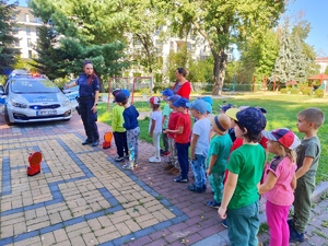 zdjęcie kolorowe: policjantka z dziećmi na podwórku przy radiowozie