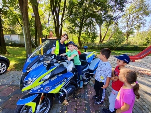 zdjęcie kolorowe: przedszkolaki stojące przy policyjnym motocyklu