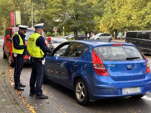 zdjęcie kolorowe: policjanci katowickiej drogówki podczas kontroli samochodu osobowego na ulicy Złotej