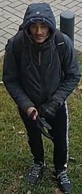 zdjęcie kolorowe: mężczyzna ubrany w czarne spodnie dresowe, granatową kurtkę z kapturem i czarnym plecakiem