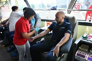 zdjęcie kolorowe: policjant oddający honorowe krew w ambulansie krwiodastwa