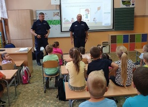 zdjęcie kolorowe: dwóch  policjantów dzielnicowych podczas spotkania z uczniami