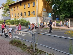 zdjęcie kolorowe: dwóch  policjantów dzielnicowych podczas nauki uczniów w zakresie bezpiecznego przechodzenia przez jezdnię