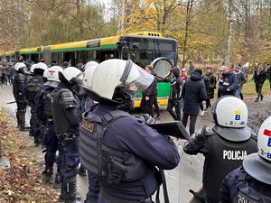 zdjęcie kolorowe: policjanci oddziału prewencji nadzorujący przemarsz pseudokibiców na stadion