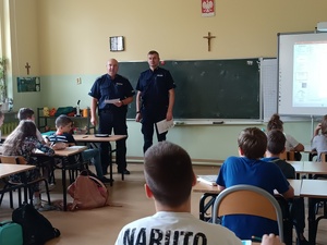 zdjęcie kolorowe: dwóch policjantów dzielnicowych podczas prelekcji z uczniami klas V szkoły podstawowej