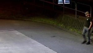 zdjęcie kolorowe: młody mężczyzna ubrany w niebieskie spodnie, czarna koszulkę z krótkim rękawem i czarną czapkę z daszkiem