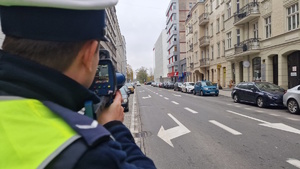 Zdjęcie kolorowe: policjant dokonuje pomiaru prędkości samochodu