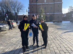 zdjęcie kolorowe: Policjantka i Strażniczki Miejskie trzymające odblaski