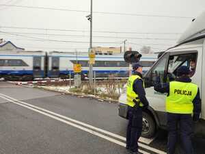 zdjęcie kolorowe: Policjant i Funkcjonariusz Straży Ochrony Kolei rozmawiają z kierowcą pojazdu