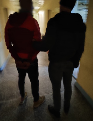 zdjęcie kolorowe: zatrzymany mężczyzna z policjantem na korytarzu komendy