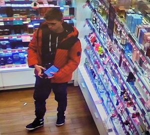 zdjęcie kolorowe: młody mężczyzna w pomarańczowej kurtce podejrzewany o kradzież perfum