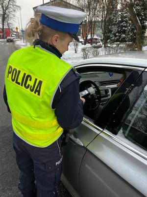 zdjęcie kolorowe: policjantka ruchu drogowego podczas kontroli trzeźwości kierujących