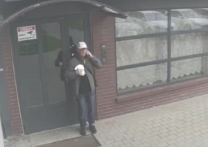 zdjęcie kolorowe: mężczyzna ubrany w granatowe spodnie, czarą kurtkę, trzymający biały worek foliowy w ręce