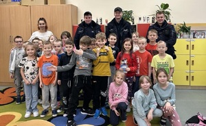 zdjęcie kolorowe: 3 dzielnicowych podczas pamiątkowego zdjęcia z uczniami klasy I szkoły podstawowej