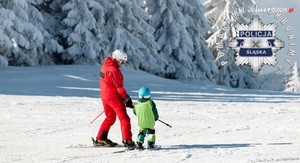zdjęcie kolorowe: mężczyzna zjeżdżający z dzieckiem na nartach ze stpku