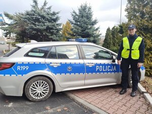 zdjęcie kolorowe przedstawiające policjantkę stojącą przy radiowozie