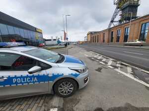 zdjęcie kolorowe przedstawiające radiowóz na tle drogi oraz budynku