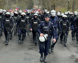 zdjęcie kolorowe: policjanci oddziału prewencji prowadzący pseudokibiców na mecz