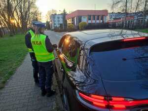 zdjęcie kolorowe: policjantka i policjant katowickiej drogówki podczas kontroli drogowej samochodu osobowego