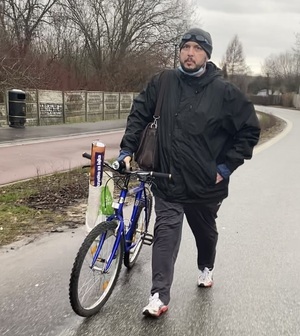 zdjęcie kolorowe: mężczyzna podejrzewany o kierowanie gróźb karalnych, ubrany w szare spodnie, czarną kurtkę, czarna czapkę