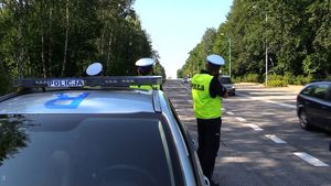 zdjęcie kolorowe: policjant katowickiej drogówki podczas mierzenia prędkości z jaka porusza się samochód