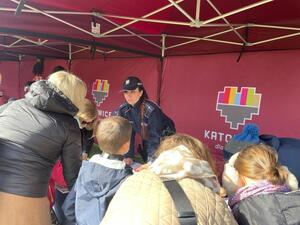 zdjęcie kolorowe: policjantka katowickiej komendy podczas rozmów z uczestnikami pikniku na stanowisku profilaktycznym