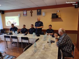 zdjęcie kolorowe: pięciu policjantów siedzących przy stole podczas spotkania z działkowcami