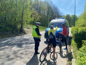 zdjęcie kolorowe: policjant drogówki rozmawiający z dwoma rowerzystami