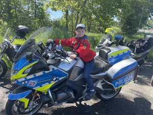 zdjęcie kolorowe przedstawiające chłopca siedzącego na policyjnym motocyklu