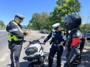 zdjęcie kolorowe przedstawiające policjantów umundurowanych  podczas działań pod nazwą &quot;zmieścimy się wszyscy&quot; rozmawiających z kierowcą motocykla