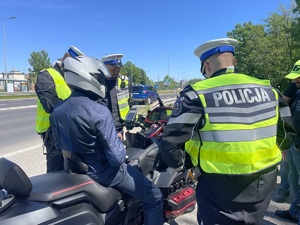 zdjęcie kolorowe przedstawiające policjantów umundurowanych  podczas działań pod nazwą &quot;zmieścimy się wszyscy&quot; rozmawiających z kierowcą motocykla