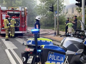 zdjęcie kolorowe przedstawiające policjantów oraz Straż Pożarną podczas akcji gaśniczej płonącego pustostanu