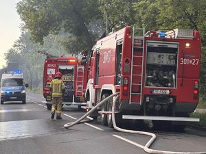 zdjęcie kolorowe przedstawiające policjantów oraz Straż Pożarną podczas akcji gaśniczej płonącego pustostanu