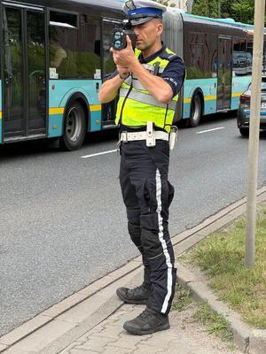 zdjęcie kolorowe przedstawiające policjanta dokonującego pomiaru prędkości