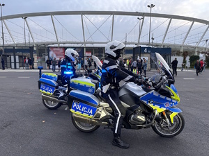 zdjęcie kolorowe: policjanci katowickiej drogówki siedzący na motocyklach służbowych przed Stadionem Śląskim