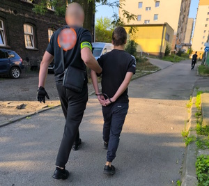 zdjęcie kolorowe: policjant z wydziału do walki z przestępczością pseudokibiców z podejrzanym o rozbój