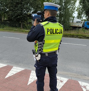 zdjęcie kolorowe: policjant katowickiej drogówki mierzący prędkość z jaką porusza się samochód