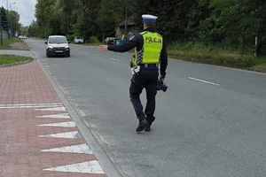 zdjęcie kolorowe: policjant katowickiej drogówki mierzący prędkość z jaką porusza się samochód