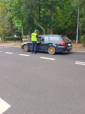 Zdjęcie kolorowe, funkcjonariusz dokonujący kontroli trzeźwości