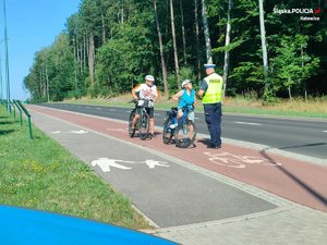 zdjęcie kolorowe: policjant rozmawiający z rowerzystami