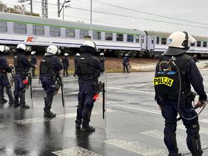 zdjęcie kolorowe: policjanci oddziału prewencji zabezpieczający przemarsz kibiców na mecz piłki nożnej rozegrany pomiędzy drużynami GKS-u Katowice i Pogoni Szczecin