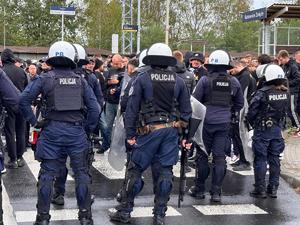 zdjęcie kolorowe: policjanci oddziału prewencji zabezpieczający przemarsz kibiców na mecz piłki nożnej rozegrany pomiędzy drużynami GKS-u Katowice i Pogoni Szczecin