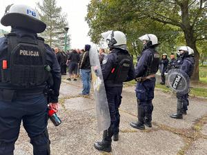 zdjęcie kolorowe: policjanci oddziału prewencji zabezpieczający przemarsz kibiców na mecz piłki nożnej rozegrany pomiędzy drużynami GKS-u Katowice i Pogoni Szczecin