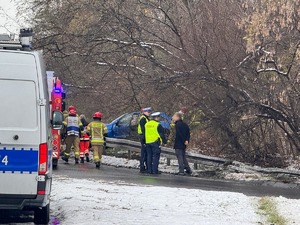 Na zdjęciu radiowóz, policjanci, strażacy, ratownicy medyczni oraz pojazd za barierami