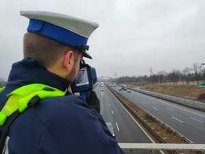 Na zdjęciu widoczny umundurowany policjant mierzący prędkość za pomocą miernika prędkości